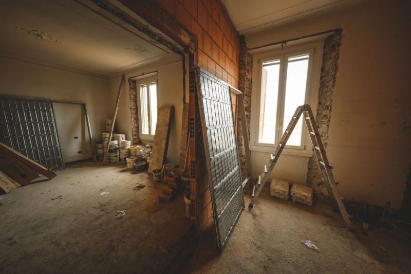Interior room mid-renovation with exposed brick, ladder, and building materials
